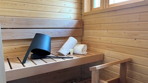 Un banco de madera con un objeto negro encima, una toalla enrollada y un pequeño recipiente.