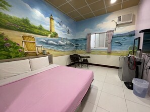 A room with a bed, a desk, a chair, a TV, and a mural of a beach scene. - Baisha B&B (Liuqiu)