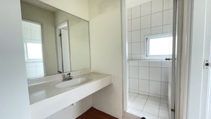 A bathroom with a white sink, a mirror, and a tiled shower area.