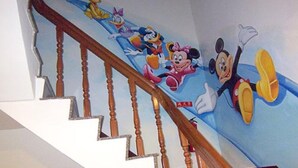 A staircase with a handrail and a wall mural featuring animated characters.