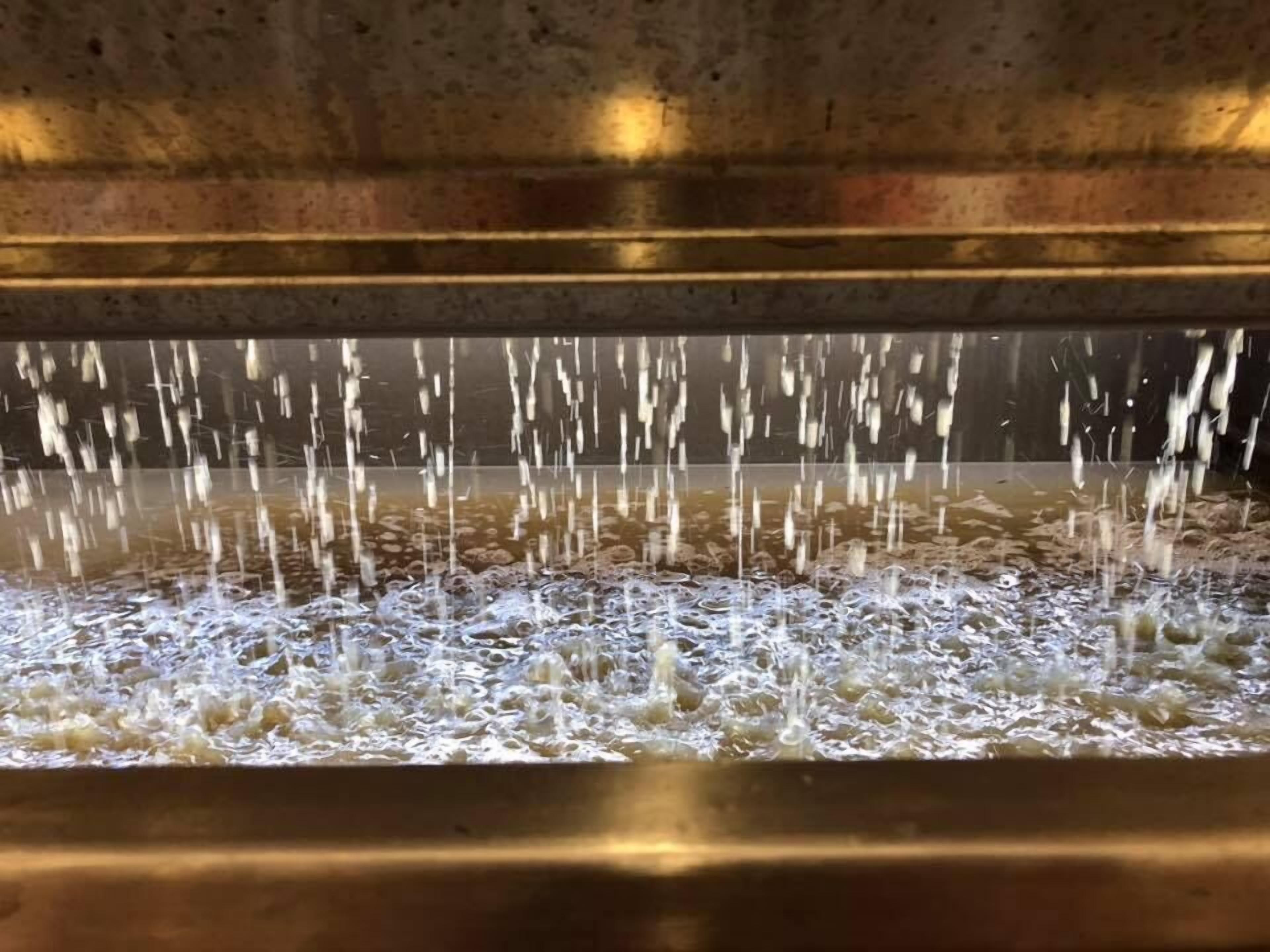 A close-up of a water feature with multiple streams of water flowing into a pool.