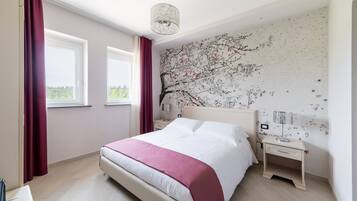 Una camera da letto moderna con un letto grande, un comodino, una lampada e un affresco sulla parete.