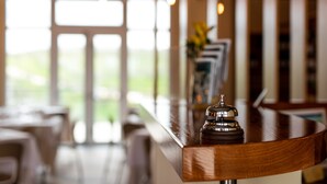 A bar area with a wooden counter, a bell, and a view of the outdoors through large windows. - Il Podere di Marfisa (Farnese)