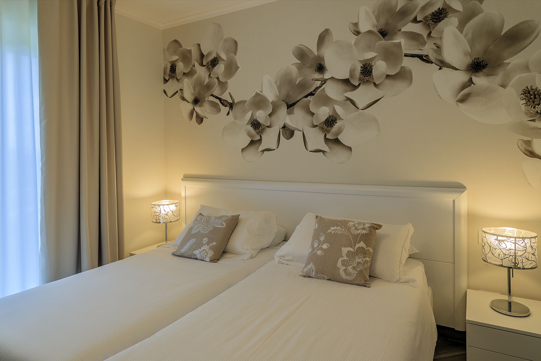 Una habitación de hotel con una cama grande, dos lámparas de noche y una obra de arte floral en la pared.