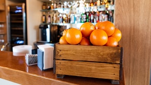 A wooden crate filled with oranges on a counter with a bar in the background. - Il Podere di Marfisa (Farnese)