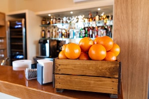 A wooden crate filled with oranges on a counter with a bar in the background. - Il Podere di Marfisa (Farnese)