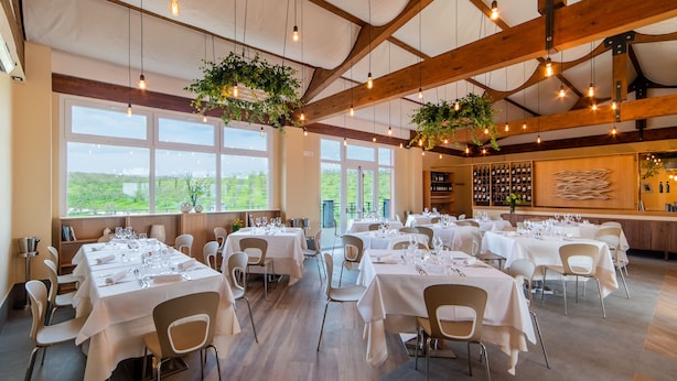 A spacious dining area with multiple tables set for dining, large windows offering a view of the outdoors, and a wine display wall. - Il Podere di Marfisa (Farnese)