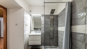 A modern bathroom with a glass shower enclosure, a wooden floor, and a white sink. - Apartman Baron (Cesky Krumlov)