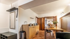 A compact kitchen with a wooden countertop, a sink, and a dining area with a table and chairs. - Apartman Baron (Cesky Krumlov)