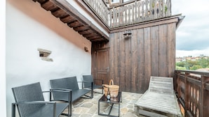 A patio with stone flooring, a wooden door, and two wicker chairs. - Apartman Baron (Cesky Krumlov)