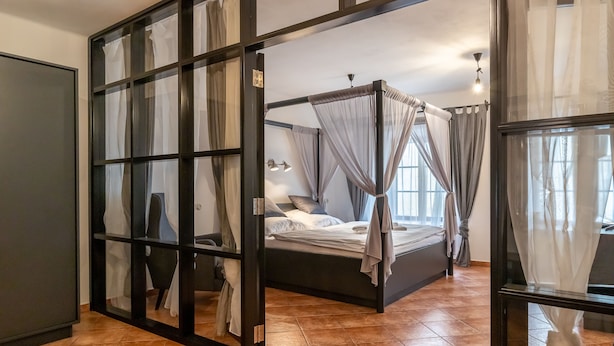 A bedroom with a four-poster bed, a desk, and a chair. - Apartman Baron (Cesky Krumlov)