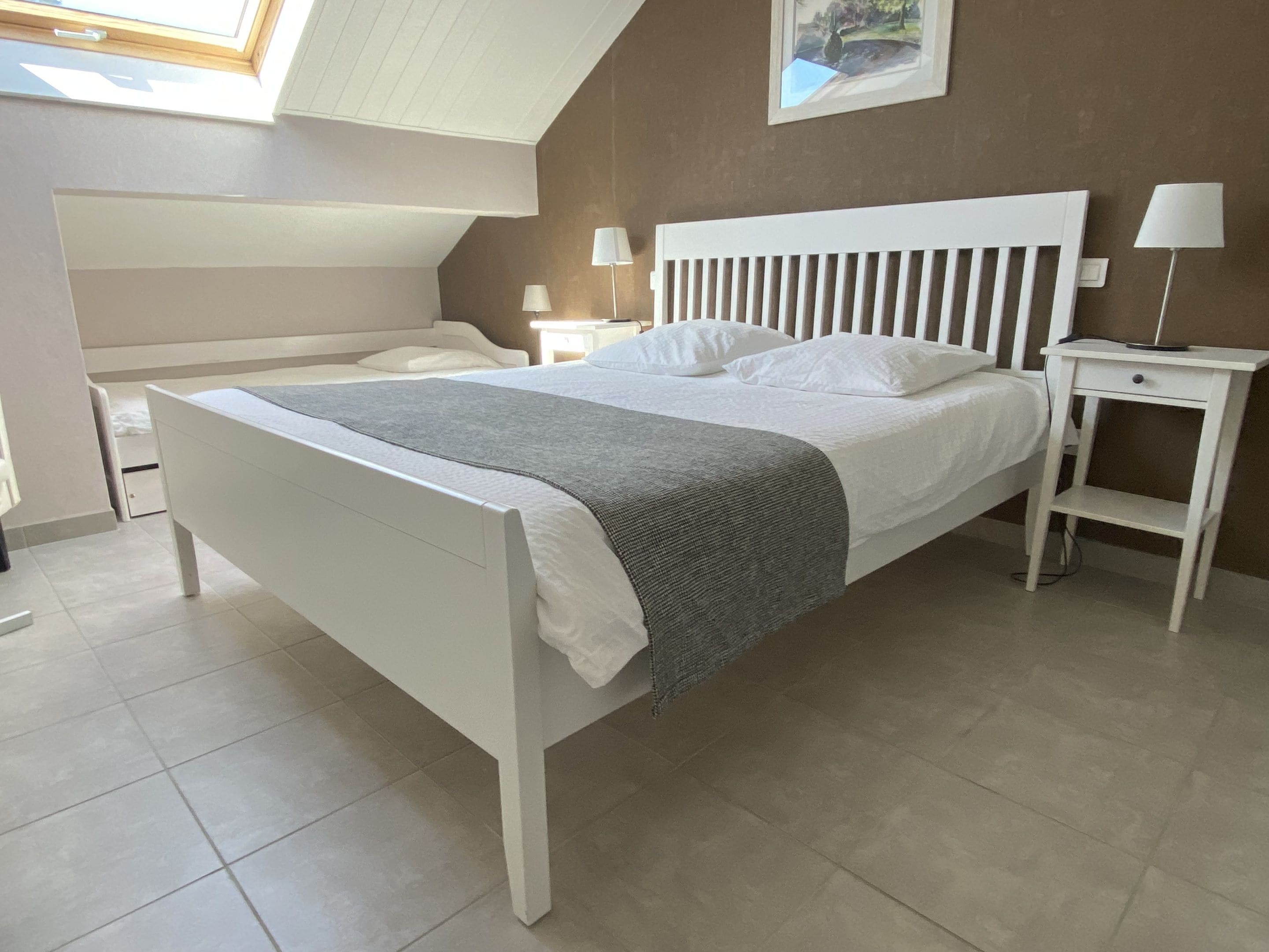 A modern bedroom with a large bed, bedside tables, and a skylight.