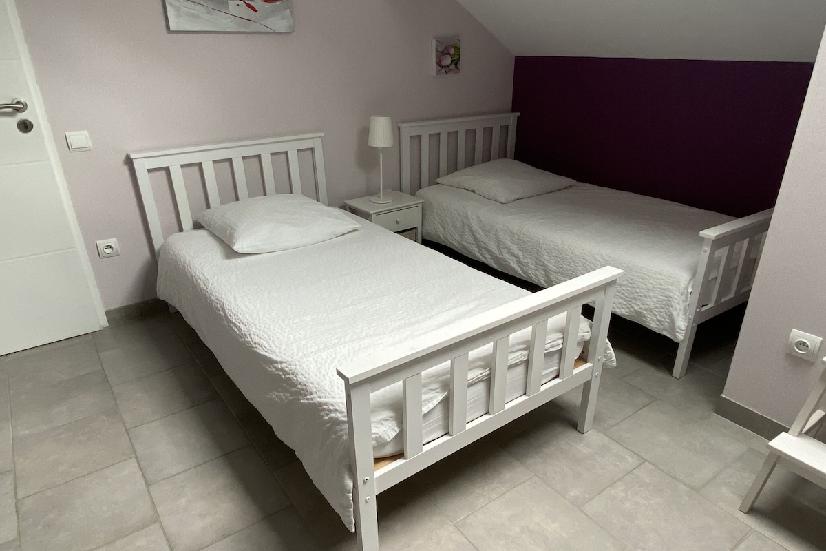 Un dormitorio con dos camas individuales, una mesita de noche, una lámpara y un pequeño marco de fotos en la pared.