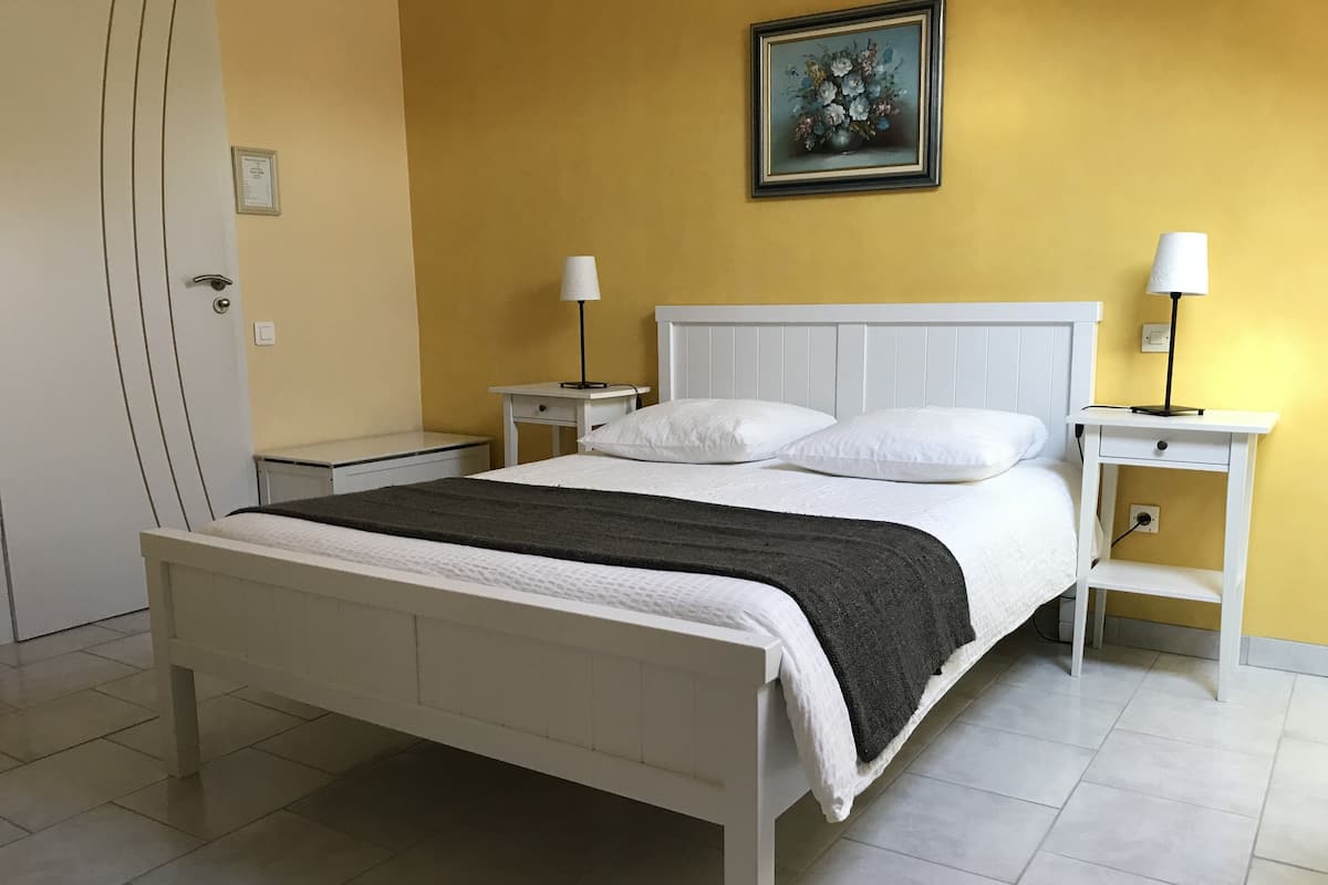 Une chambre à coucher bien rangée, avec un lit, des tables de chevet et un tableau accroché au mur.
