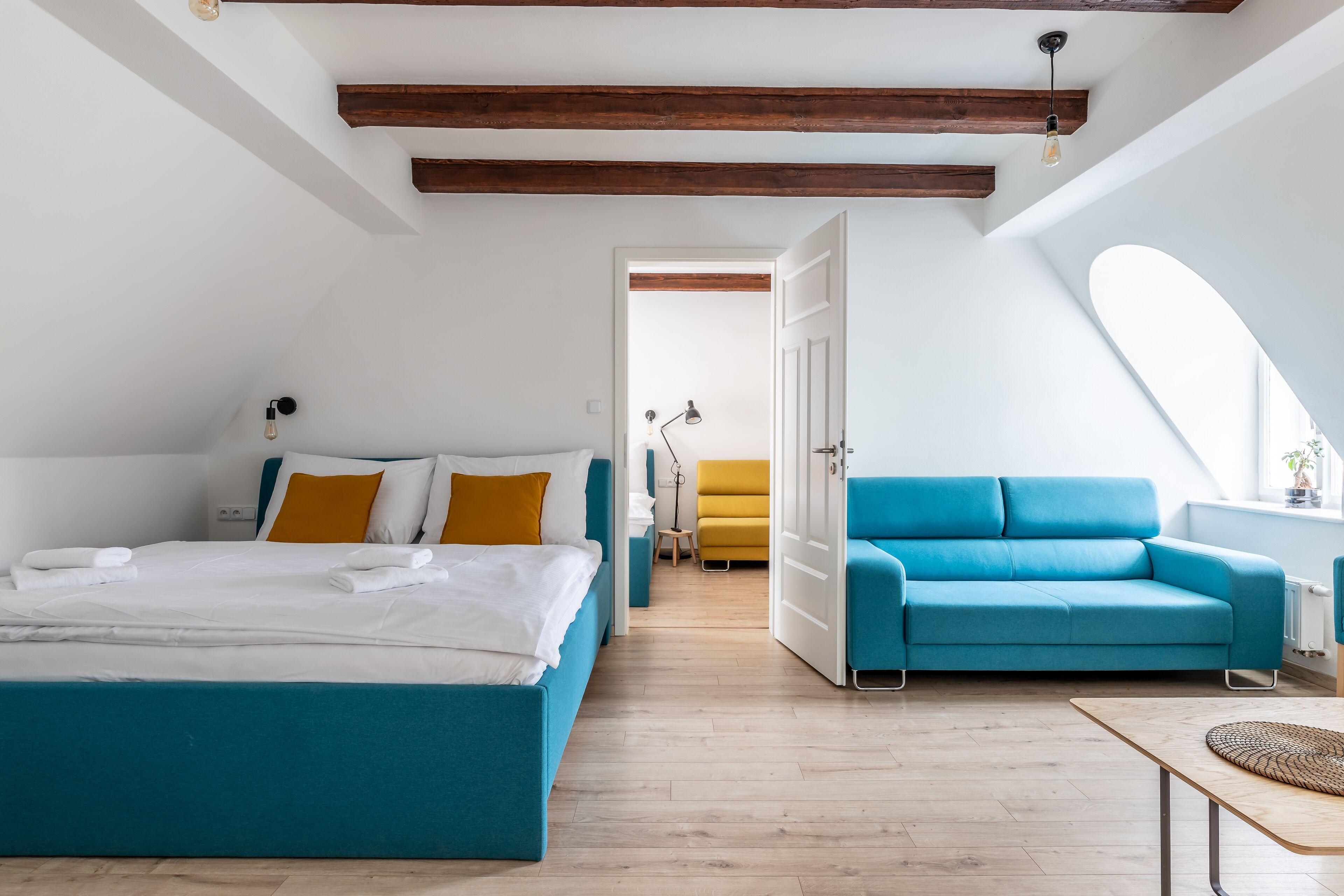 Una camera da letto moderna con un letto grande, un divano blu e un soffitto in legno.
