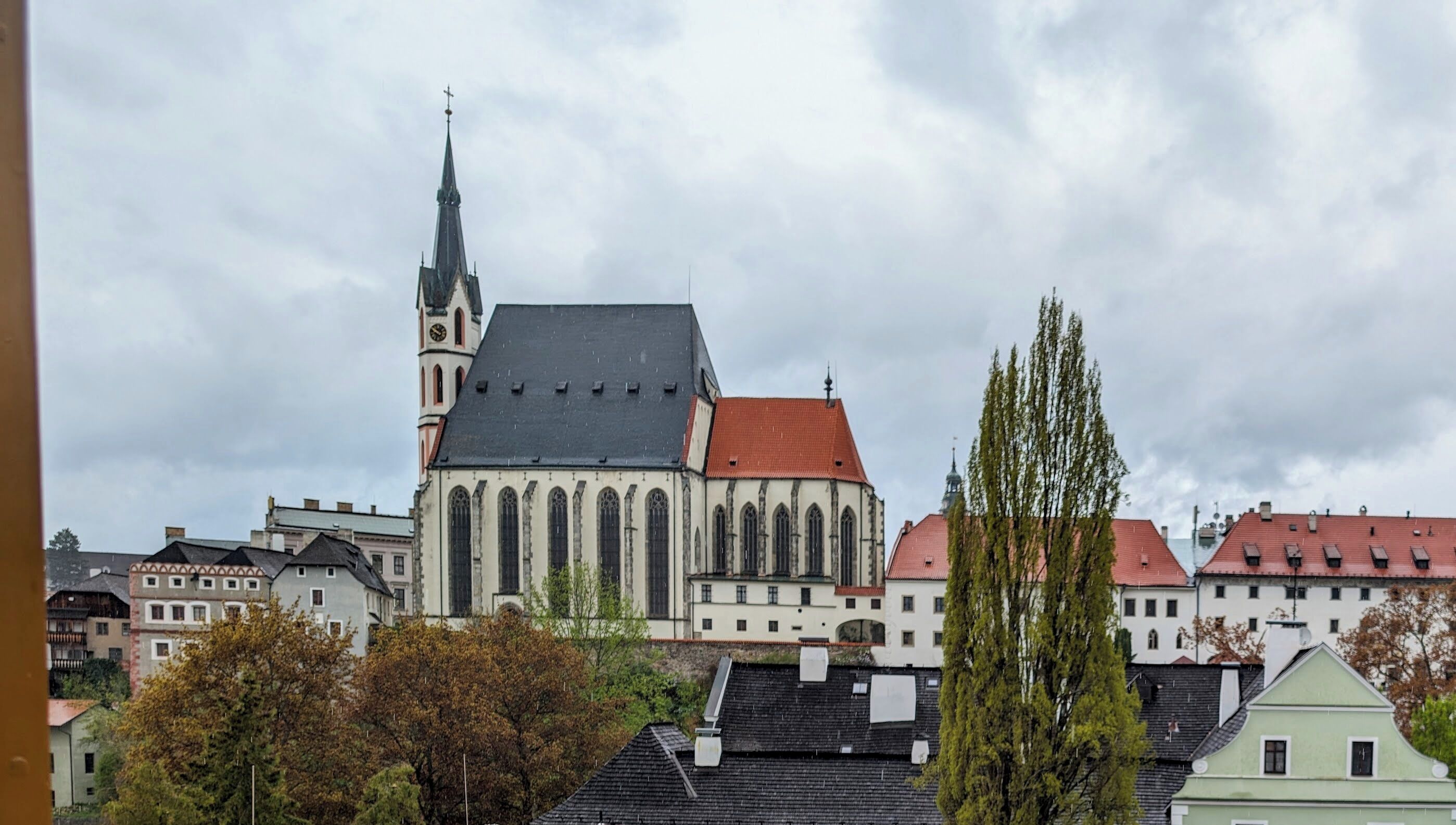 En historisk kirke med et markant spir og tilstødende boligbygninger.