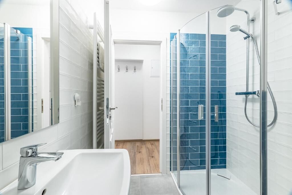 A modern bathroom with a glass shower enclosure, a white sink, and a mirror.