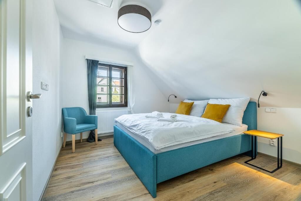 A bedroom with a bed, a chair, a window, and a skylight.