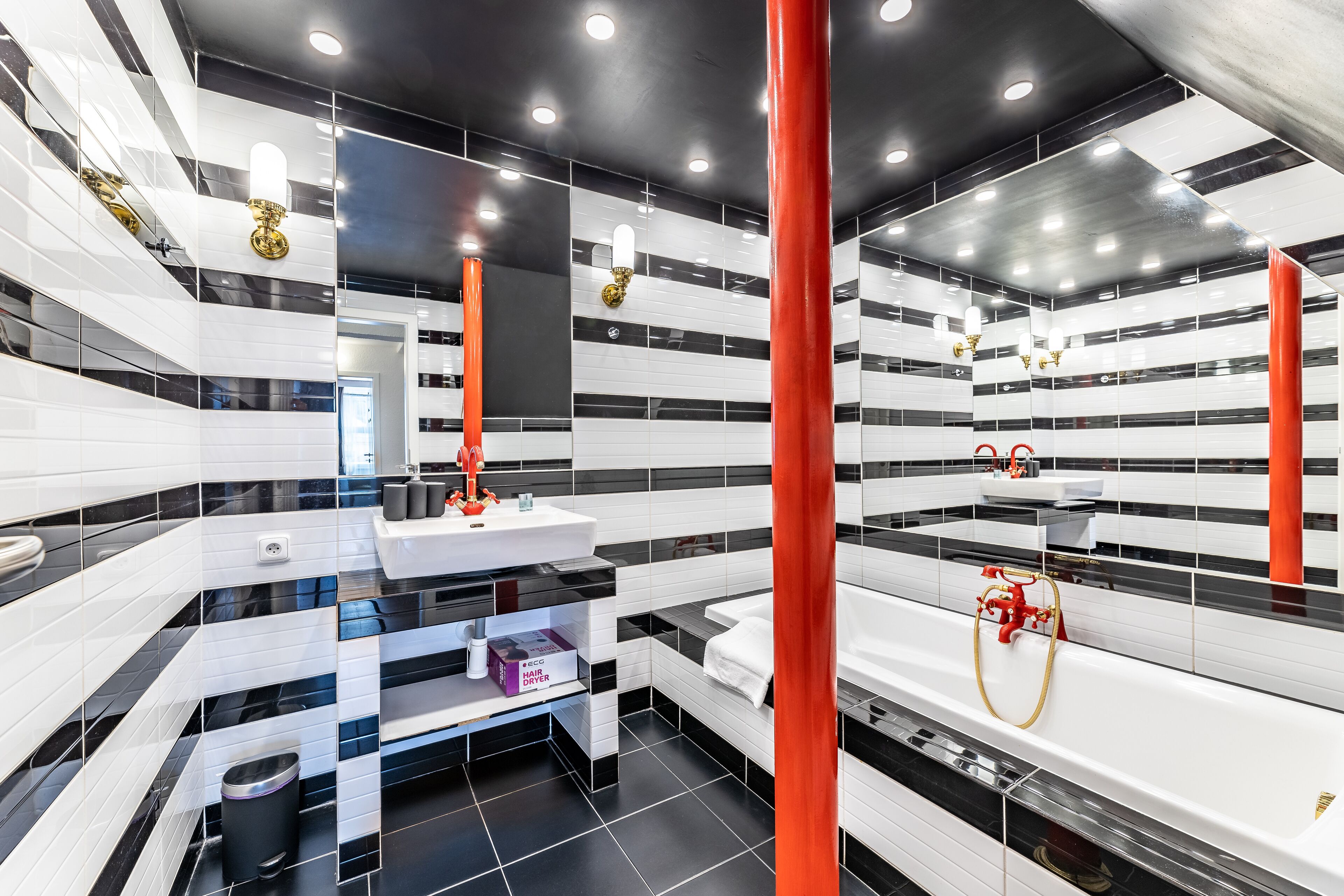 Ein modernes Badezimmer mit schwarz-weißen Fliesen, einem weißen Waschbecken und einer Badewanne.