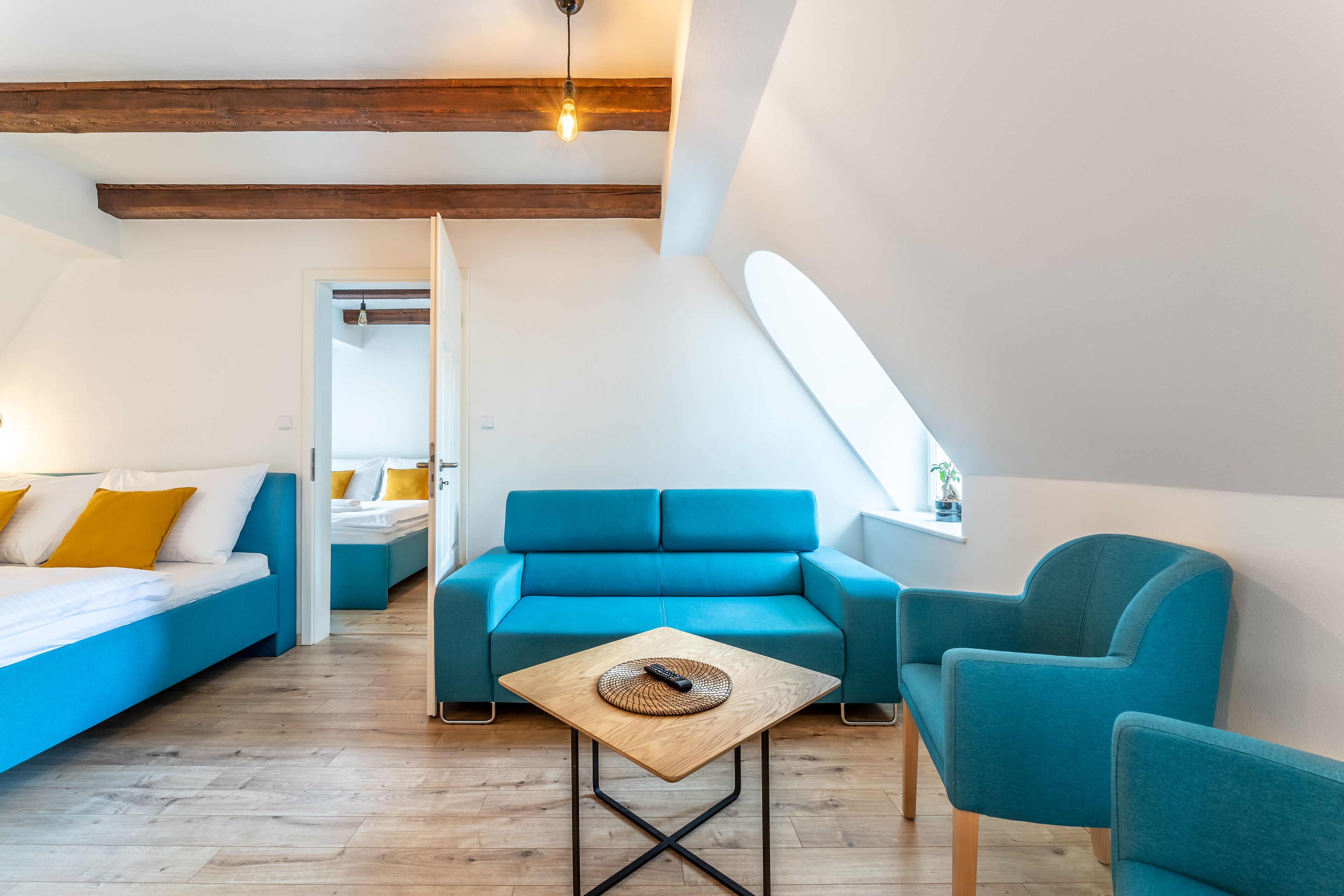 Une chambre de style loft moderne, avec un canapé bleu, une table basse en bois et une grande fenêtre.