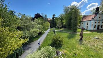 A pathway leading to a building with a bell tower, surrounded by greenery and trees.