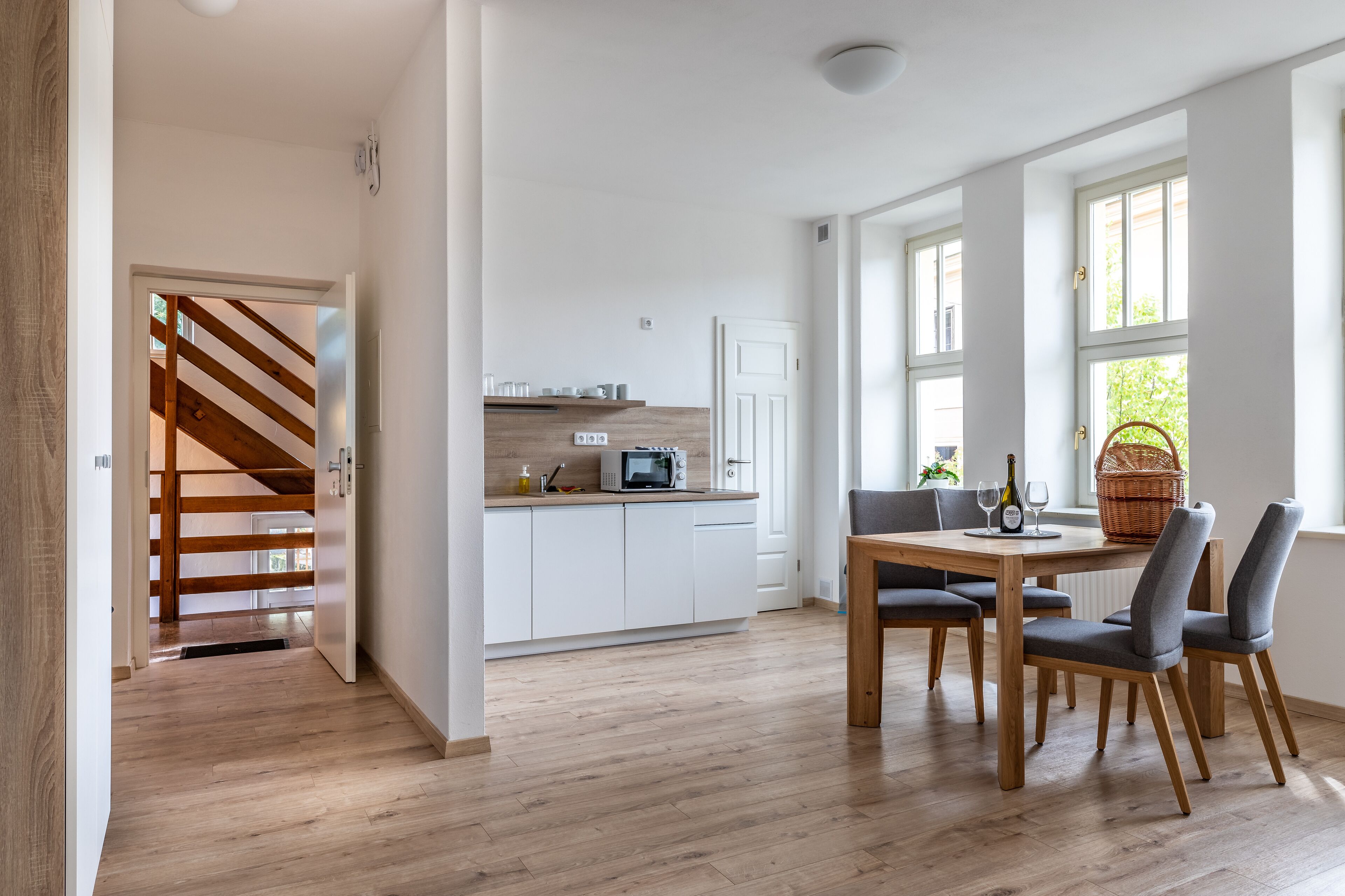 A modern kitchen with white cabinets, a microwave, and a dining area with a wooden table and chairs.