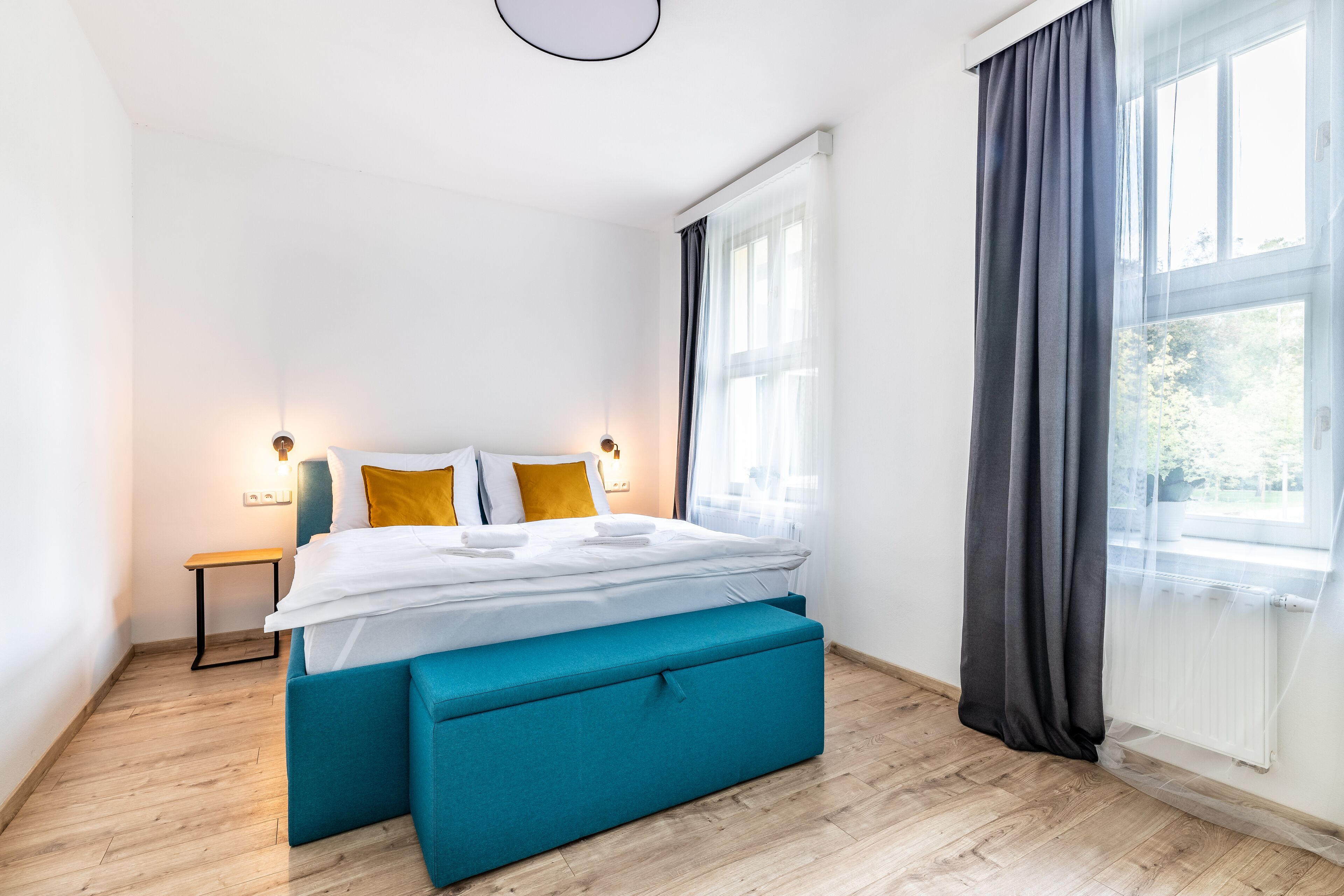 Un dormitorio moderno con cama, mesitas de noche y una ventana con cortinas.