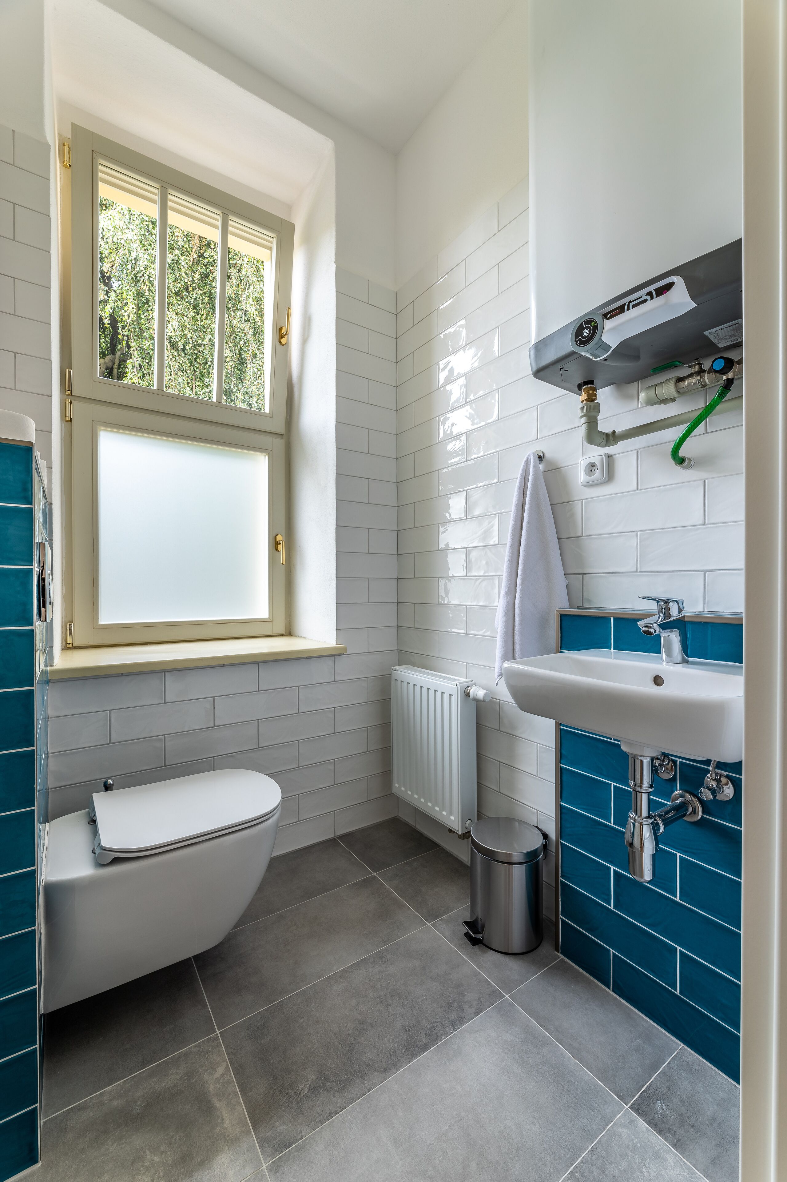Ein Badezimmer mit Toilette, Waschbecken, Fenster und Heizkörper.