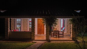 A stone building with a wooden door, a bench, and a table outside. - Doric Cottages Diani (Diani Beach)