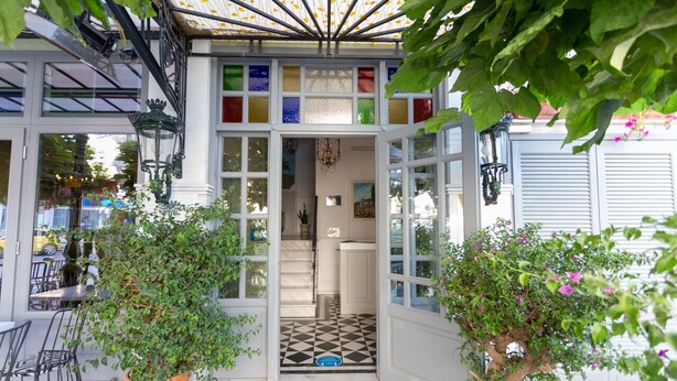 Une véranda dotée d’une porte vitrée, d’un sol à carreaux noirs et blancs et de plantes en pot.
