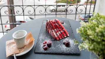 A dessert on a slate plate with a cup and napkin on a table, viewed from a balcony with a metal railing.