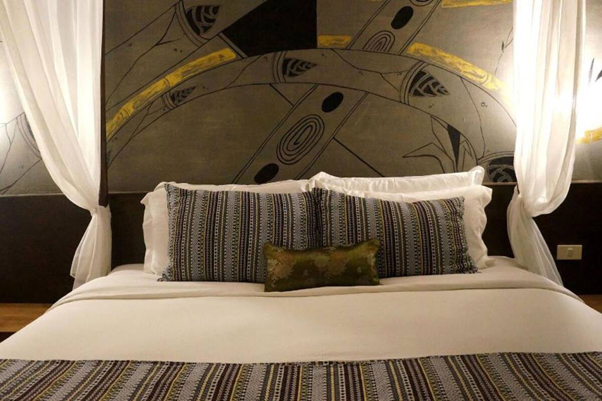 A bed with a canopy, patterned pillows, and a striped bedspread.