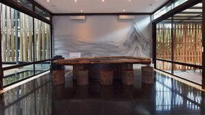 Uma área de recepção moderna com um amplo balcão de madeira, uma obra de arte na parede e um painel de vidro.