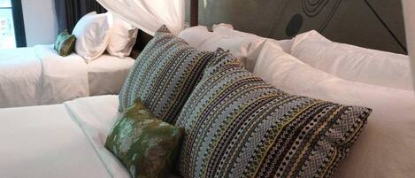 Una habitación de hotel con una cama que incluye almohadas estampadas y una almohada decorativa verde.