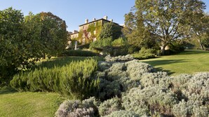 A large, historic building with a well-maintained garden featuring various shrubs and trees. - Azienda Agricola Chiarentana (Chianciano Terme)