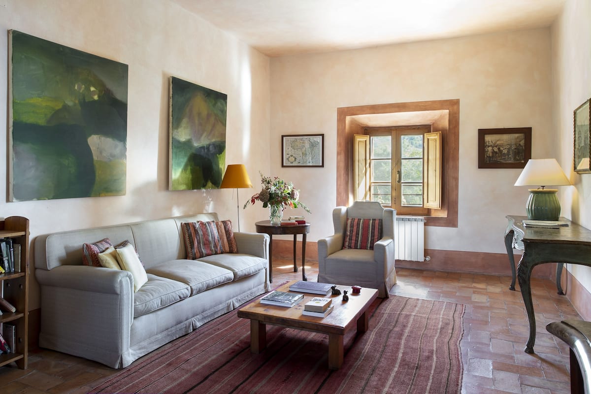 Un salon comprenant un canapé, des fauteuils, une table basse et des œuvres d’art accrochées aux murs.