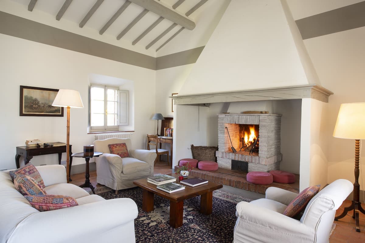 Un salon chaleureux avec une cheminée, des meubles blancs et un tapis à motifs.