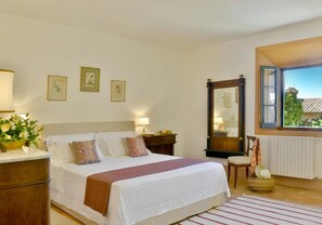 A bedroom with a bed, bedside tables, a mirror, a window, and wall art. - Azienda Agricola Chiarentana (Chianciano Terme)