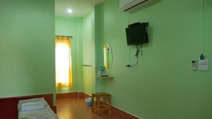 A room with a bed, a small wooden stool, a television mounted on the wall, and an air conditioning unit. - Kwanjai Resort (Tha Mai)