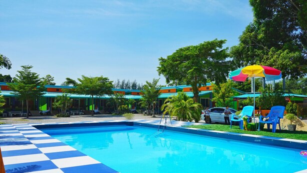A swimming pool with a checkered floor, surrounded by colorful buildings and palm trees. - Kwanjai Resort (Tha Mai)