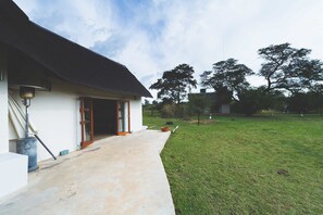 A house with a concrete porch, a thatched roof, and a grassy yard. - Deruxa Cottages (De Wagensdrift)