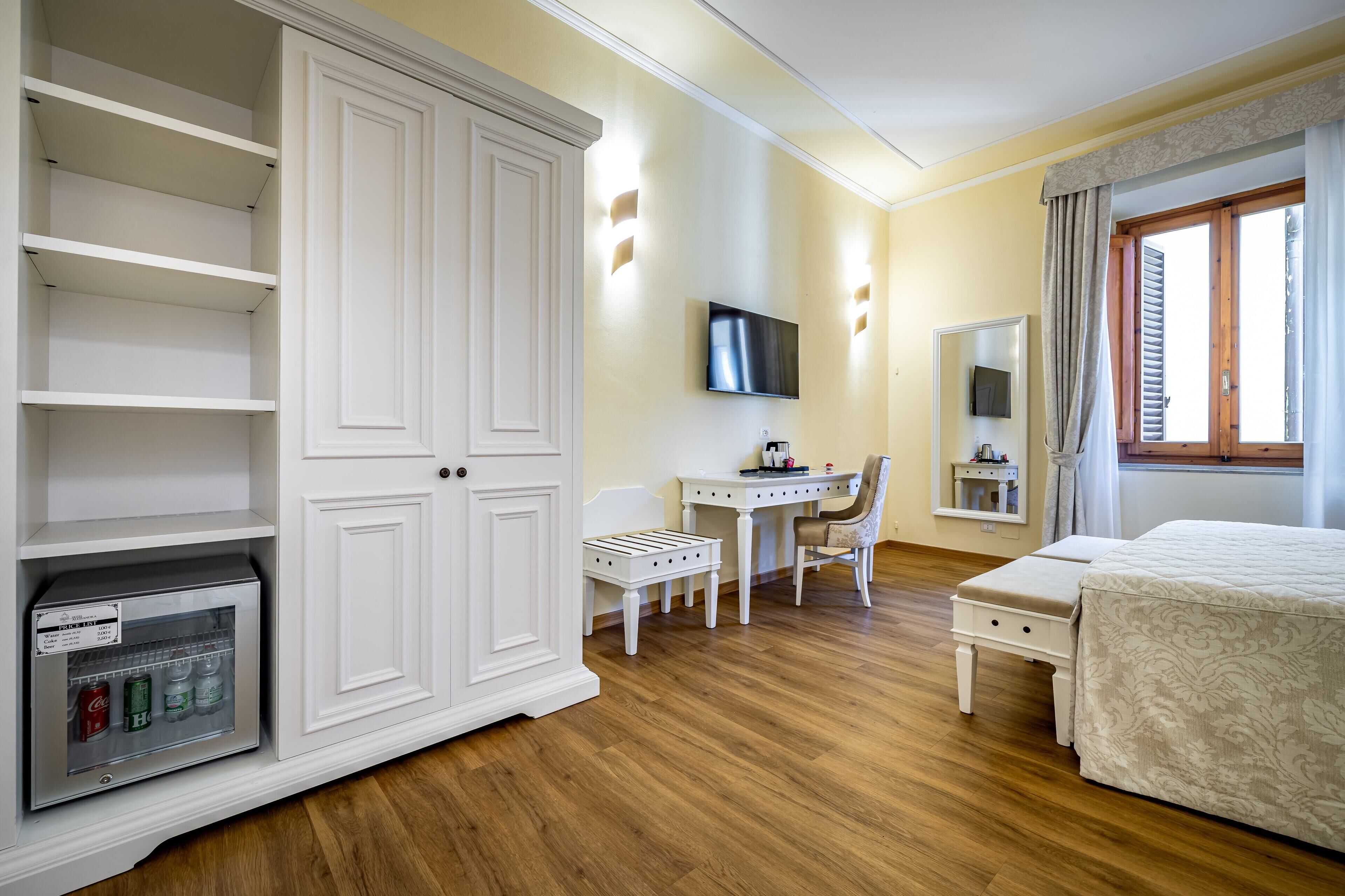 A bedroom with a bed, a desk, a chair, a wardrobe, and a television.