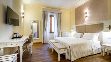 A hotel room with a bed, bedside table, chair, desk, and a TV mounted on the wall.