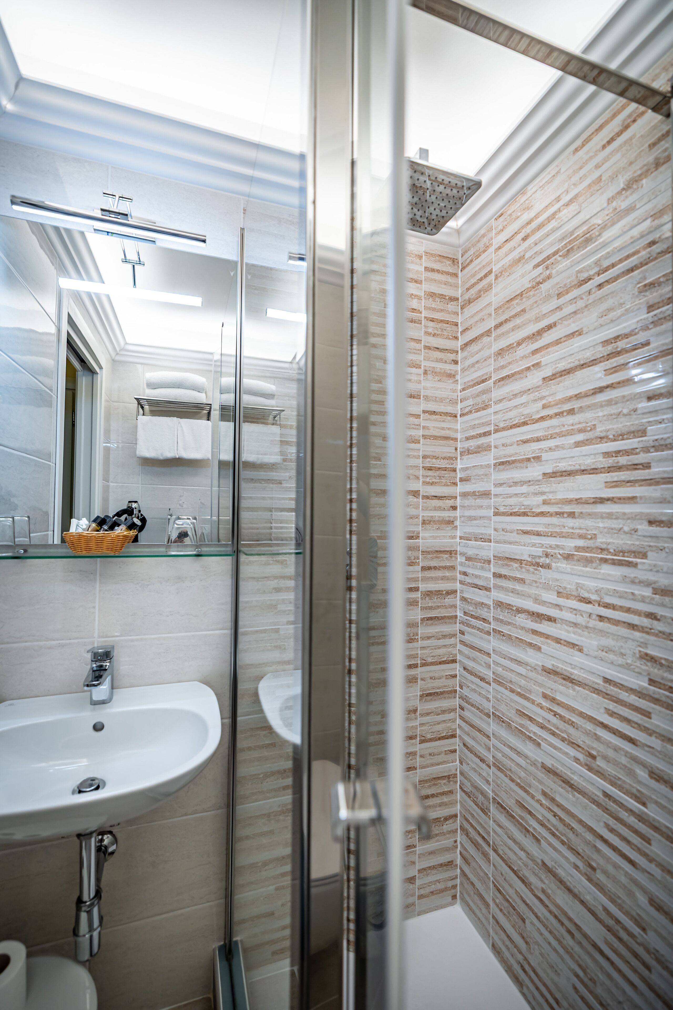 Un baño moderno con cabina de ducha de vidrio, un lavabo y un espejo.
