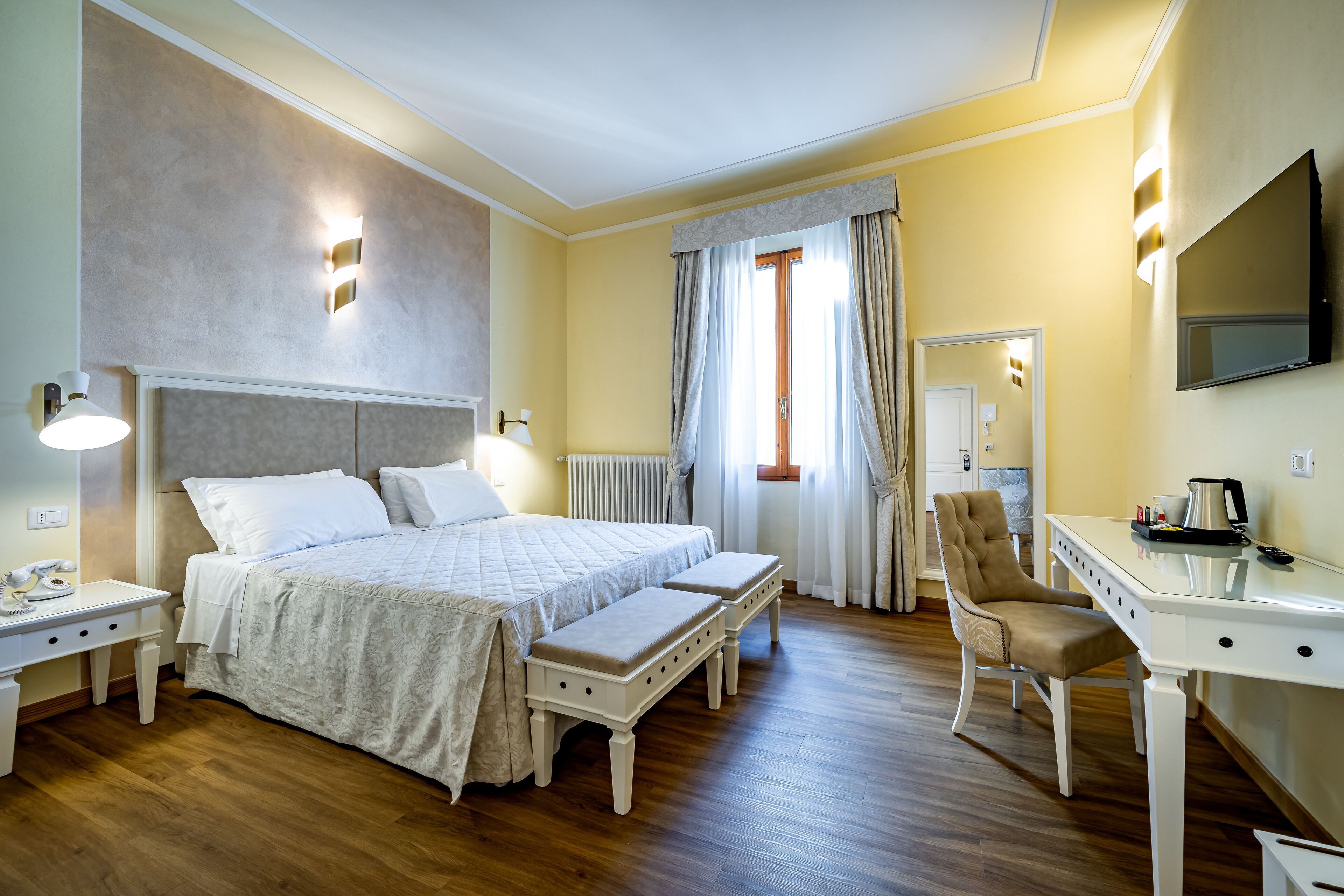 Una habitación de hotel con una cama grande, un escritorio, una silla y un televisor.