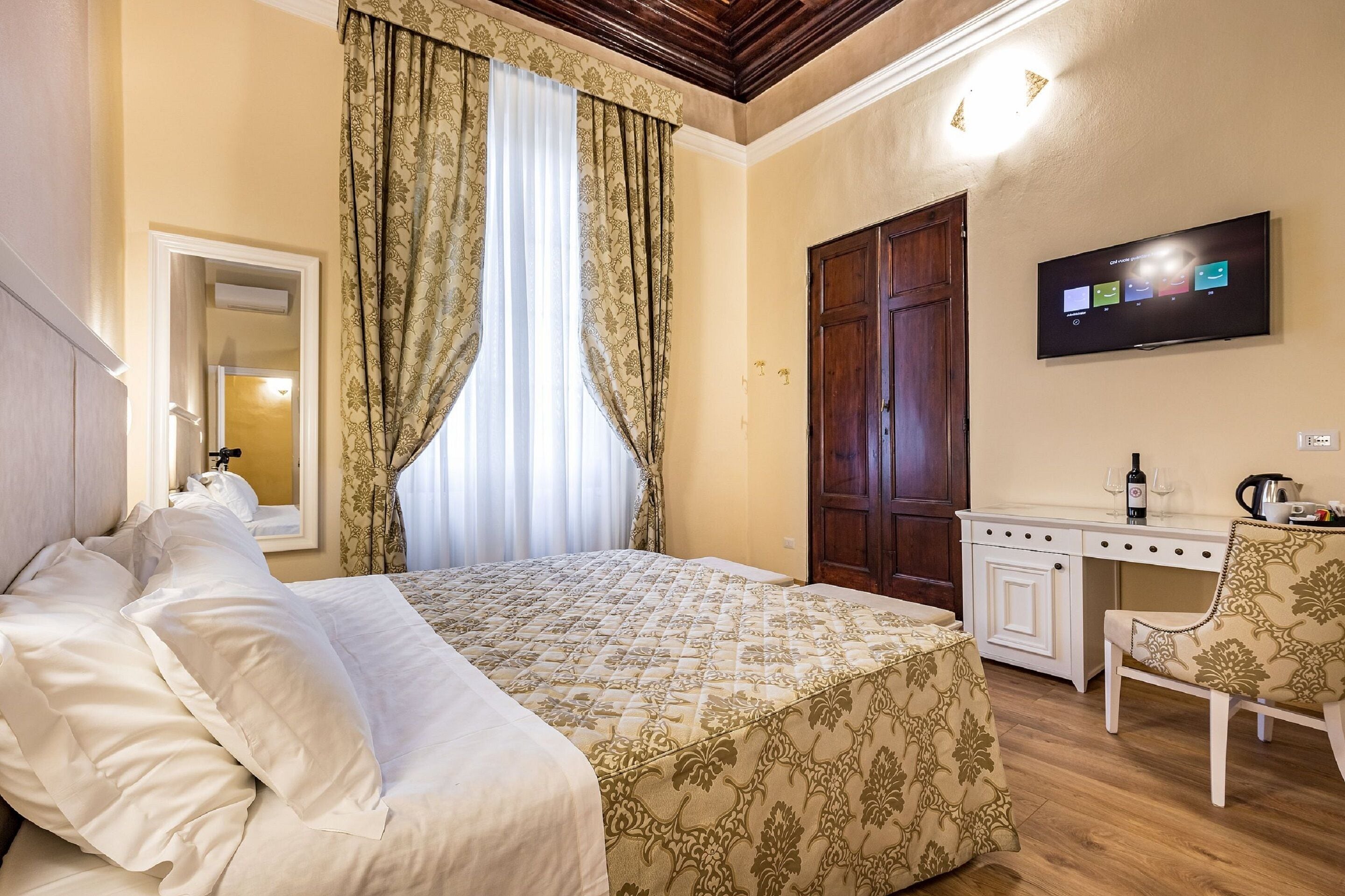 A hotel room with a bed, a desk, a chair, a television, and a wardrobe.