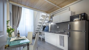 A modern kitchen with a stainless steel refrigerator, a microwave, and a glass-top dining table with a vase of flowers. - Residenza Alessandra (Florence)