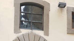 A double wooden door with a stone archway, a small window above, and a number plaque on the wall. - Residenza Alessandra (Florence)