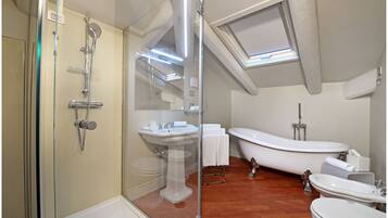 A modern bathroom with a glass-enclosed shower, a pedestal sink, a freestanding bathtub, and a separate vanity with a sink.