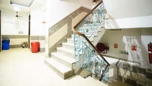 A staircase with blue metal railings and a wooden handrail, leading to an upper floor.